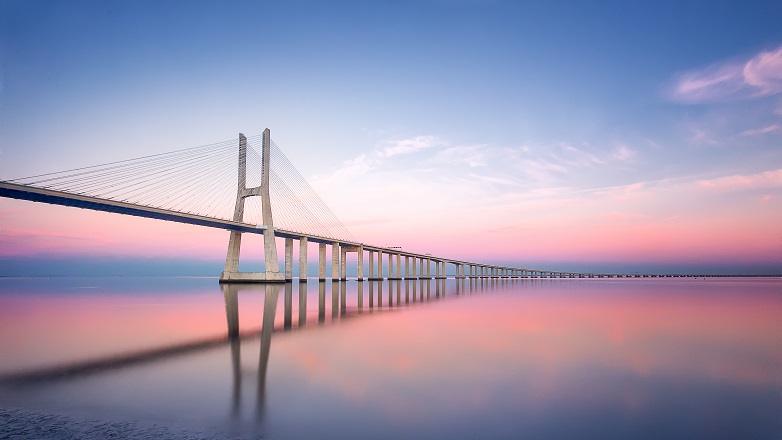 Suspension bridge over water at sunset