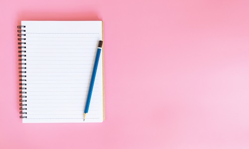 notepad and pencil on pink background