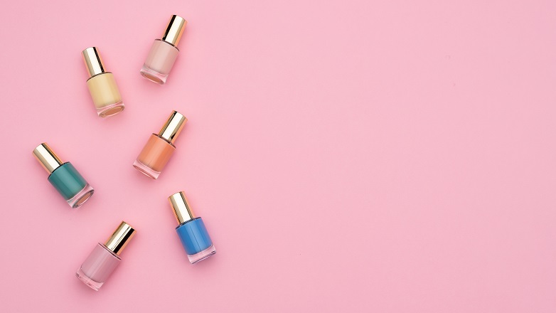 different coloured bottles of nail varnish on pink background
